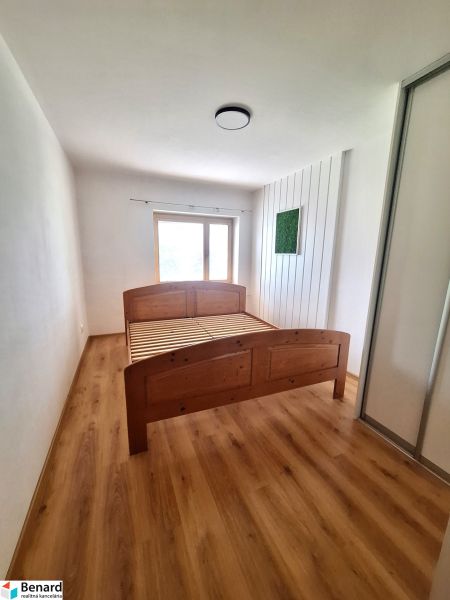 Schlafzimmer mit Holzbett und Einbauschrank in einer 2-Zimmer-Wohnung.