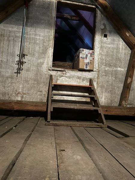 Der Dachboden des Einfamilienhauses mit einer Holztreppe und einem Paket.