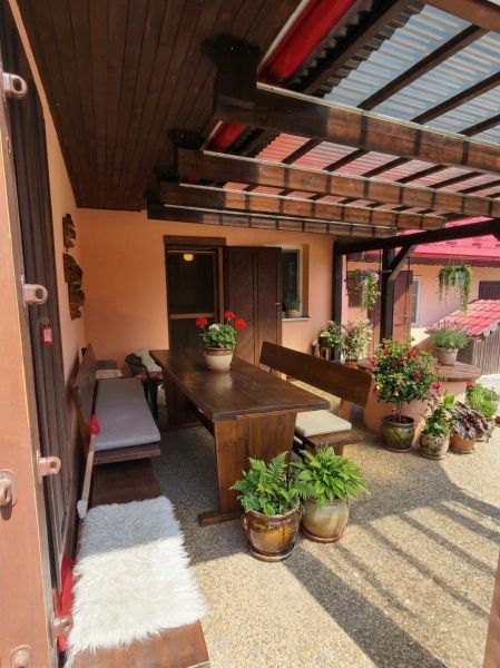 Die Terrasse des Einfamilienhauses in Lakšárska Nová Ves in Mikulášov mit Holzmöbeln und Blumen.