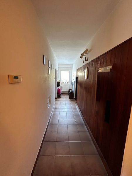 Ein Flur in einem Einfamilienhaus mit Fliesen und Holzverkleidung an der Wand.