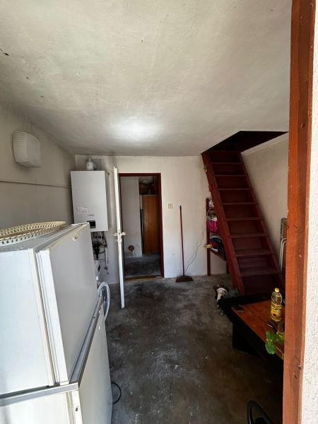 Innenraum eines Einfamilienhauses mit Kühlschrank, Boiler und Holztreppe.