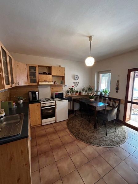Küche in einem Einfamilienhaus mit Holzschränken und einem Esstisch, umgeben von Pflanzen.