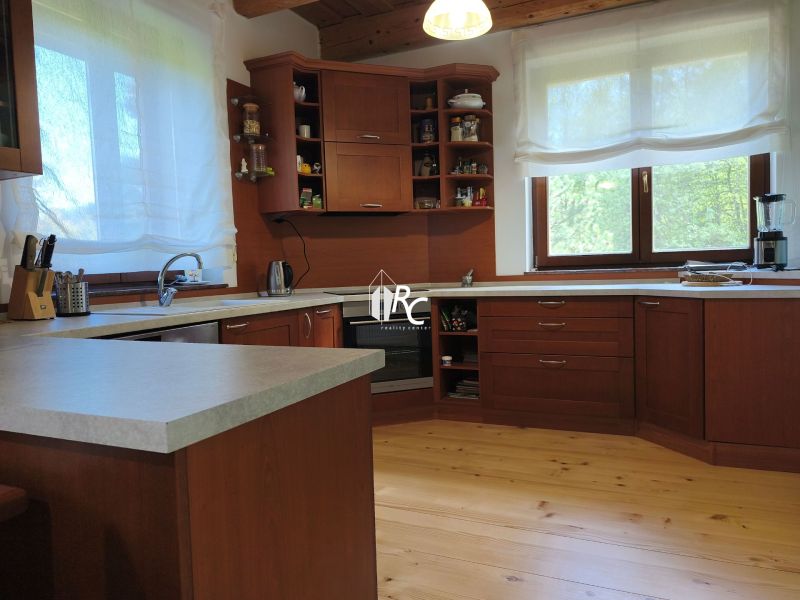 Küche in einem Einfamilienhaus mit Schränken aus dunklem Holz und einem Boden in Holzoptik.