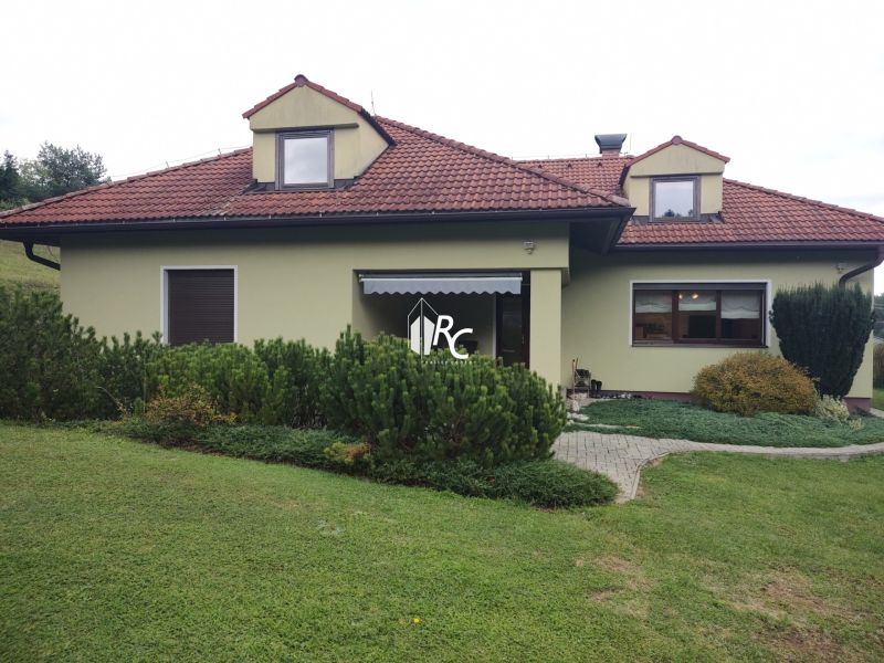 Ein Einfamilienhaus in Trebostovo mit Garten, Schrägdach und grüner Fassade.