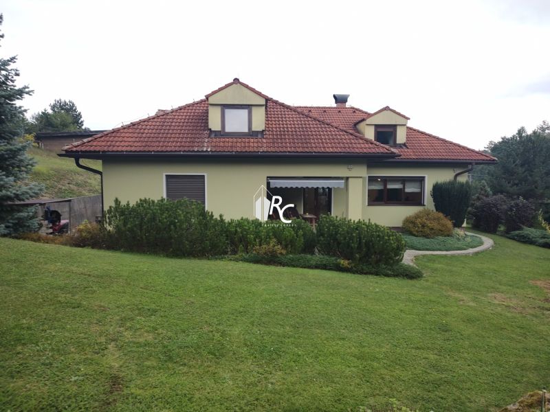 Ein Einfamilienhaus in Trebostovo mit rotem Dach, umgeben von grünem Rasen und Büschen.
