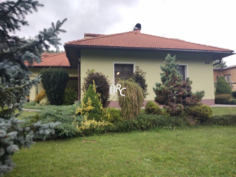 Ein Einfamilienhaus in Trebostovo, vorne ein gepflegter Garten mit Pflanzen und Bäumen.