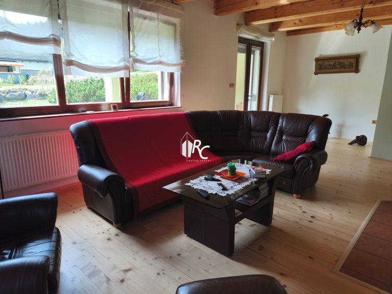 Wohnzimmer in einem Einfamilienhaus mit Ledersofas und einem Boden in Holzoptik.