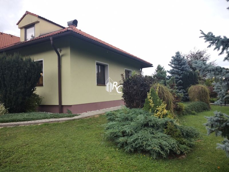 Ein Einfamilienhaus in Trebostovo mit einem gepflegten Garten und Holzelementen am Dach.