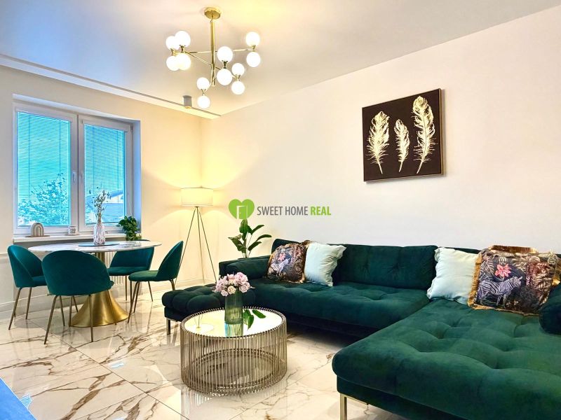 Wohnzimmer in einer 3-Zimmer-Wohnung mit einem auffälligen grünen Sofa und Marmorboden.