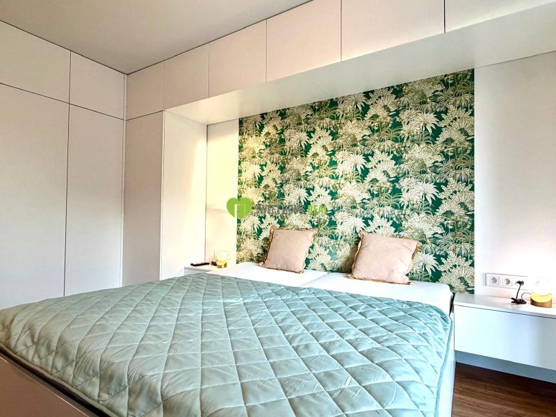 Schlafzimmer in einer 3-Zimmer-Wohnung mit Holzboden und grüner Tapete.