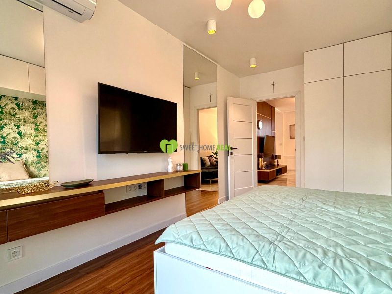 Schlafzimmer in einer 3-Zimmer-Wohnung mit Fernseher und Boden in Holzoptik.