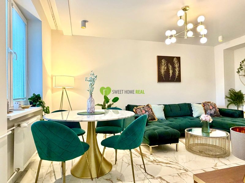 Wohnzimmer in einer 3-Zimmer-Wohnung, grünes Sofa, Marmortisch, auffällige Leuchte.