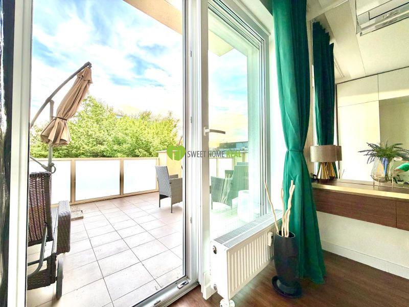 Innenraum einer 3-Zimmer-Wohnung mit Terrasse, Boden mit Holzdekor, grüne Vorhänge.