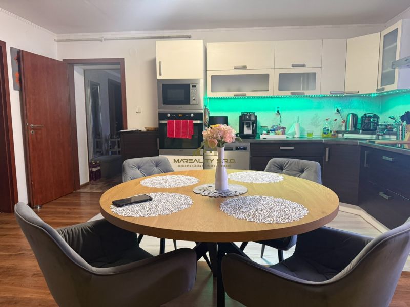 Eine Küche in einem Einfamilienhaus mit einem eleganten Tisch und einem Boden in Holzoptik.