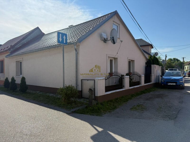 Ein Einfamilienhaus in Záhorská Ves mit einer Satellitenschüssel und einem blauen Auto, das vor dem Haus geparkt ist.