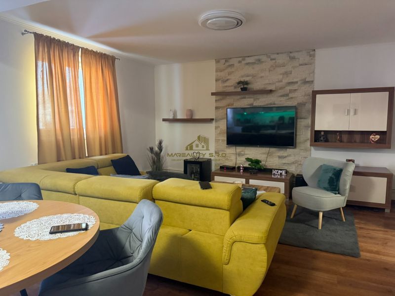 Wohnzimmer in einem Einfamilienhaus mit einem bequemen gelben Sofa und einem Boden in Holzoptik.