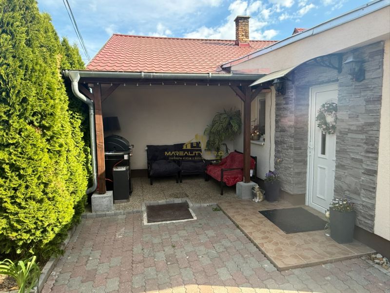 Einfamilienhaus in Záhorská Ves, Terrasse mit Sitzgelegenheit, grüne Thujen, weiße Eingangstür.