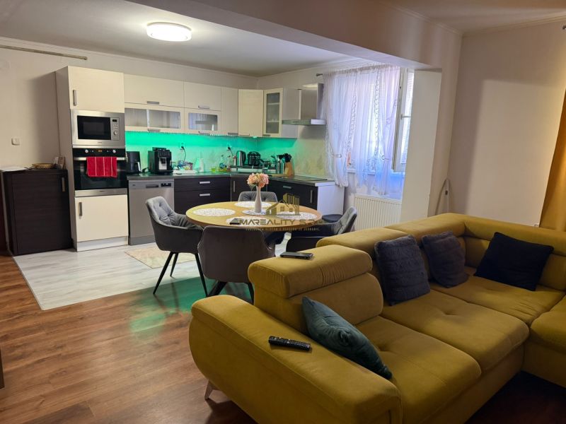 Küche und Wohnzimmer in einem Einfamilienhaus mit Holzboden und einem bequemen Sofa.