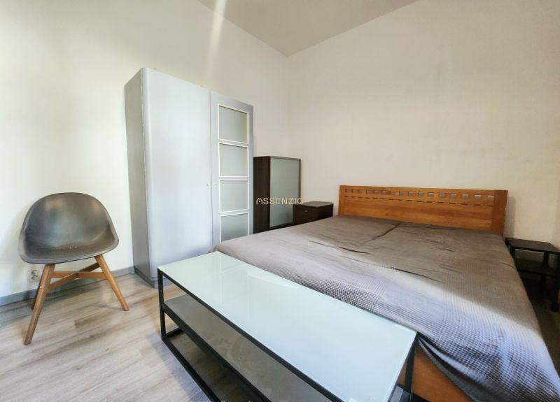 Schlafzimmer in einer 2-Zimmer-Wohnung mit Holzbett, Schrank und Stuhl.