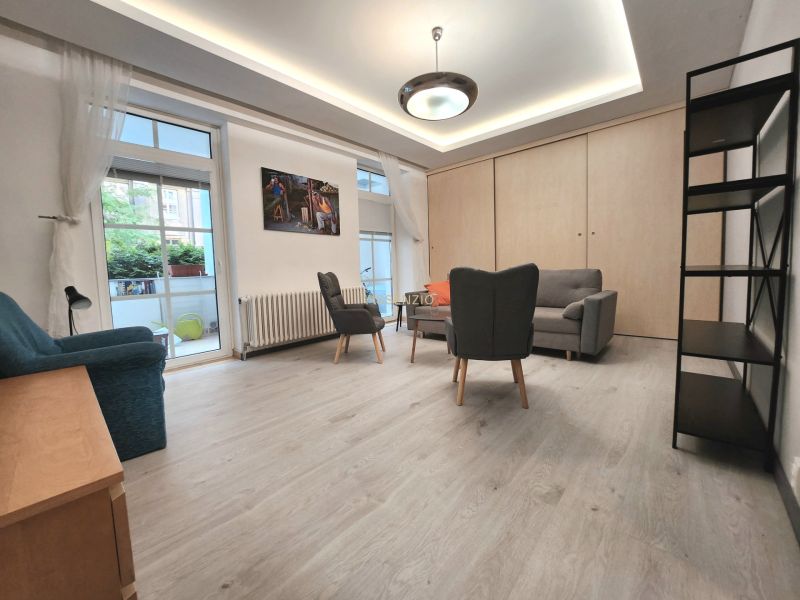 Wohnzimmer in einer 2-Zimmer-Wohnung, Boden mit Holzdekor, Möbel, große Fenster.