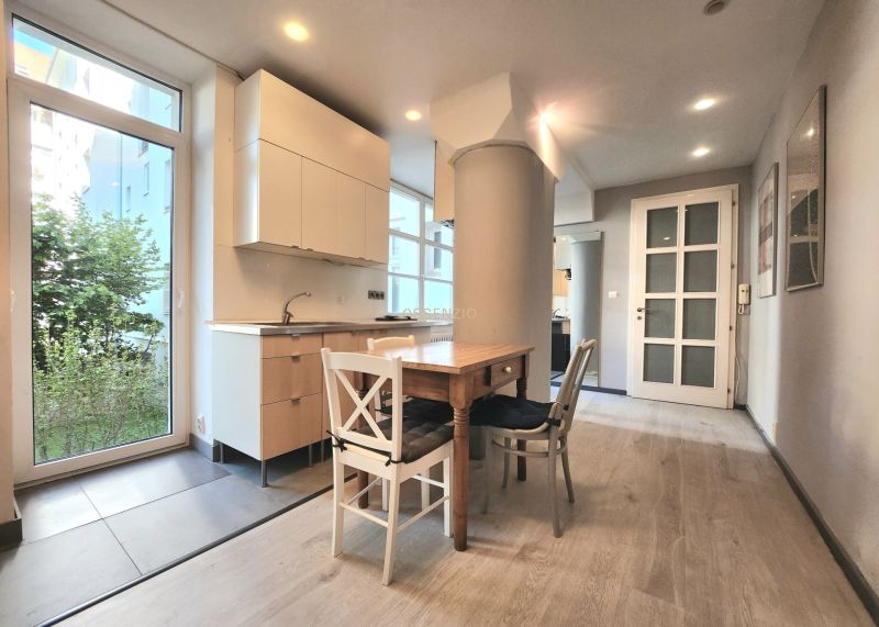 Küche in einer 2-Zimmer-Wohnung mit Holztisch und Boden in Holzoptik.
