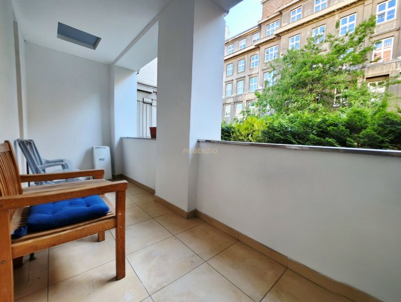 Balkon einer 2-Zimmer-Wohnung mit Blick auf Grünflächen und ein Gebäude, Sitzgelegenheit mit Stühlen.