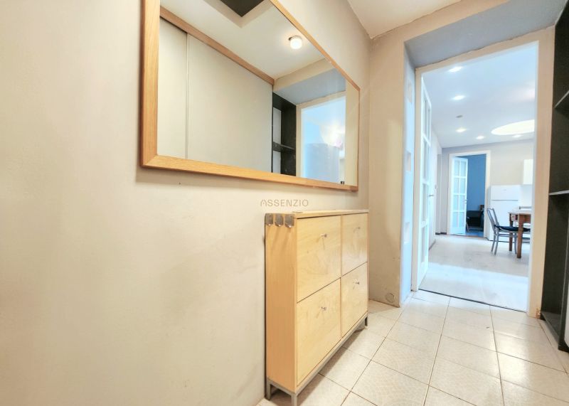 Der Flur in der 2-Zimmer-Wohnung mit Holzmöbeln, Fliesen und einem großen Spiegel.