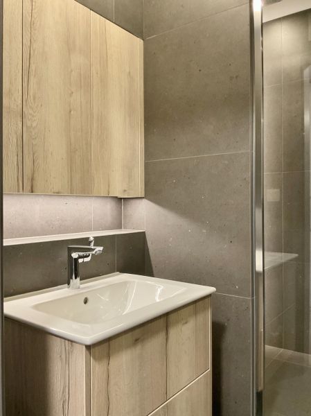Badezimmer mit hellem Holzmöbel und dunklen Fliesen in einer Einzimmerwohnung.