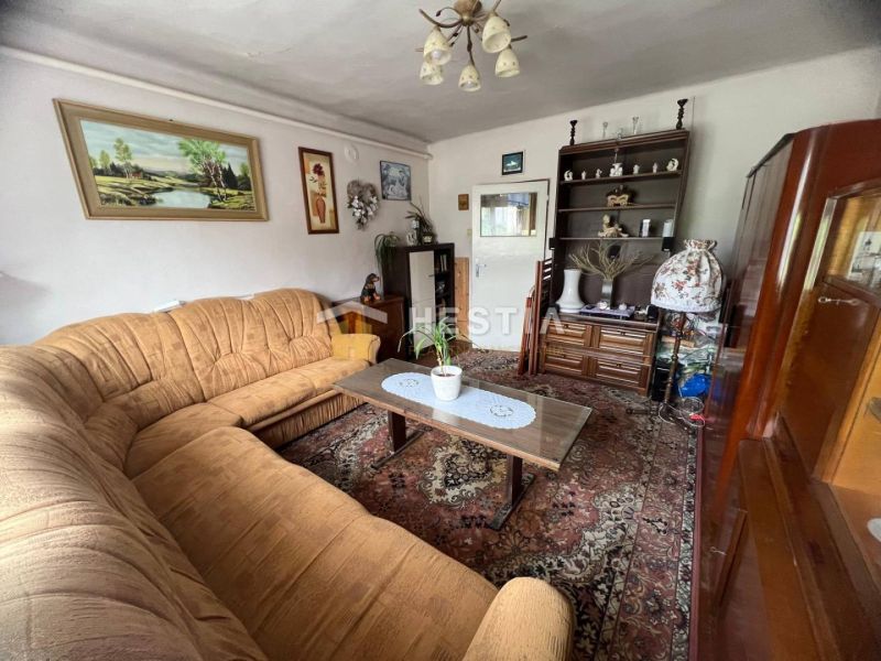 Wohnzimmer in einem Einfamilienhaus mit braunem Sofa, Teppich und dekorativen Bildern an den Wänden.