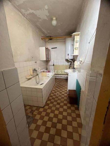 Badezimmer mit Badewanne in einem Einfamilienhaus, gefliest mit Heizkörper und Gaskessel.