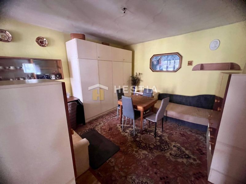 Wohnzimmer mit Teppichen, Holzelementen und einfacher Einrichtung in einem Einfamilienhaus.