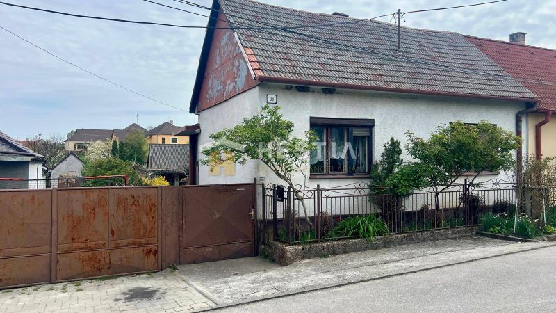 Ein Einfamilienhaus in Cerová mit einem Tor und einem kleinen Garten, umgeben von Grün.