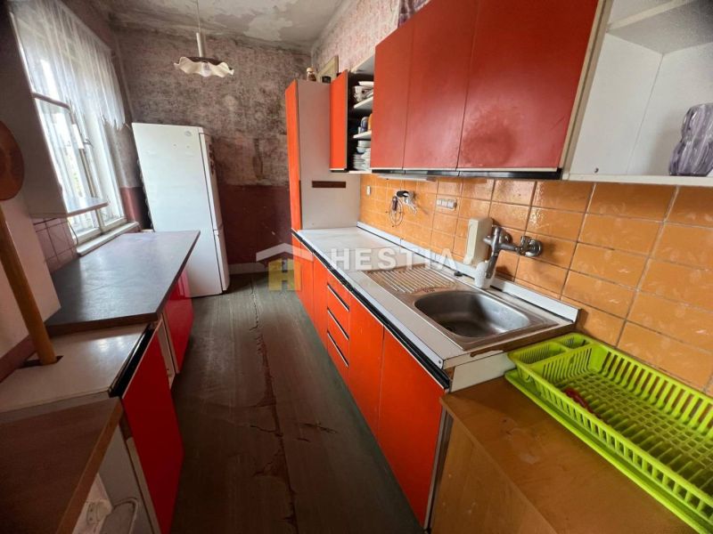 Eine Küche in einem Einfamilienhaus mit orangefarbenen Schränken und einem Boden in Holzoptik.
