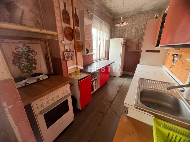 Eine Küche in einem Einfamilienhaus mit einem Boden in Holzoptik und Retro-Möbeln.