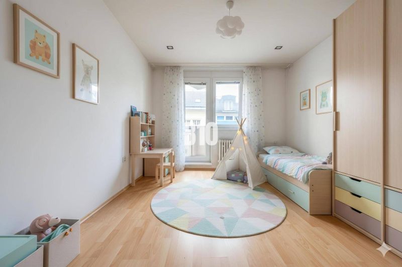Kinderzimmer in einer 4-Zimmer-Wohnung mit bunten Möbeln und einem Boden in Holzoptik.