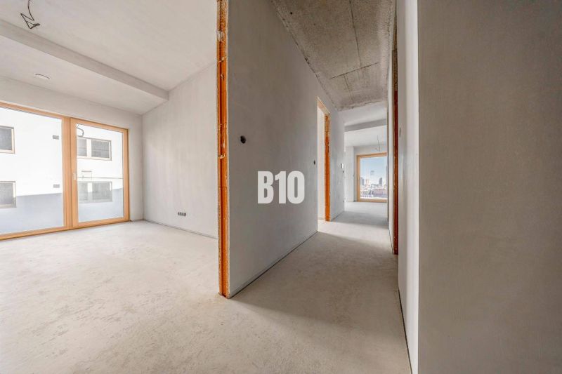 Flur in einer 3-Zimmer-Wohnung mit großen Fenstern und Betonboden.