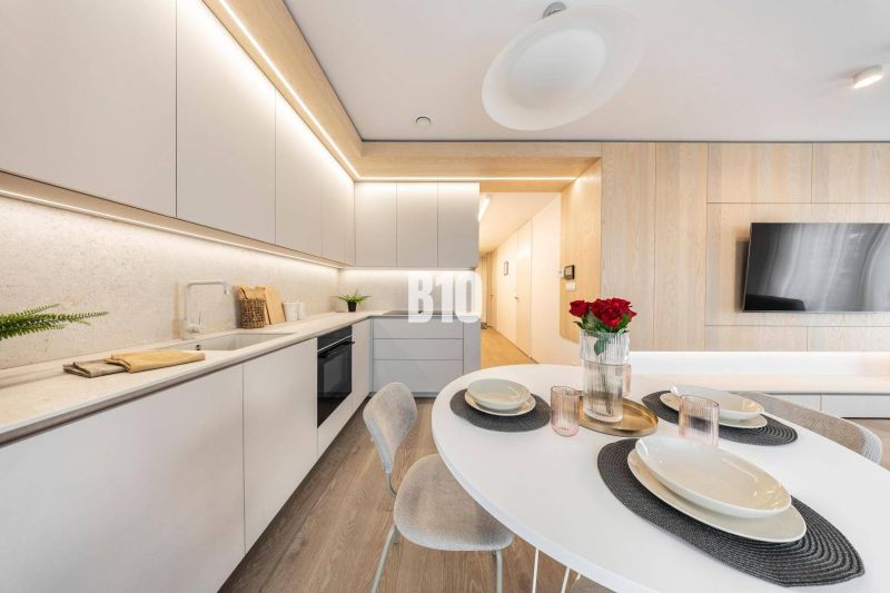 Eine stilvolle Küche in einer 3-Zimmer-Wohnung mit Holzboden und modernen Möbeln.