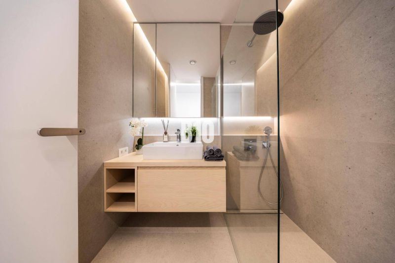 Badezimmer mit Spiegel, Dusche und Holzelementen in einer 3-Zimmer-Wohnung.