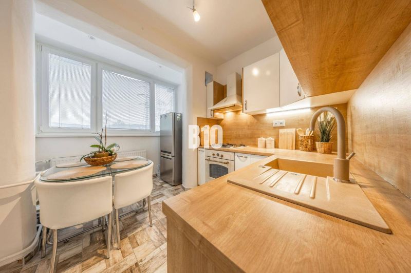 Küche in einer 2-Zimmer-Wohnung mit Holzboden und Essecke.