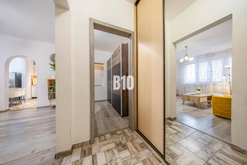 Innenraum einer 2-Zimmer-Wohnung mit Holzboden, hellem Mobiliar und bogenförmigen Durchgängen.