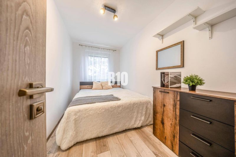 Schlafzimmer mit Bett, Kommode und Holzboden in einer 2-Zimmer-Wohnung.