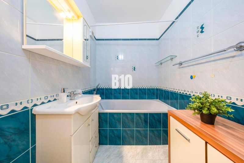 Badezimmer mit Badewanne und Waschbecken in einer 2-Zimmer-Wohnung mit blau-weißen Fliesen.
