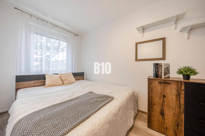 Schlafzimmer in einer 2-Zimmer-Wohnung mit Bett, Regalen und Boden mit Holzdekor.