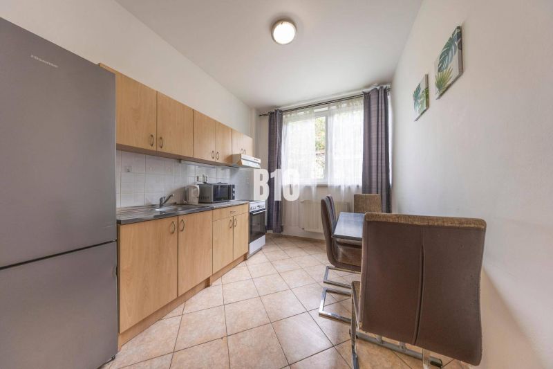 Küche mit Holzschränken, Esstisch und großem Fenster, Büros.
