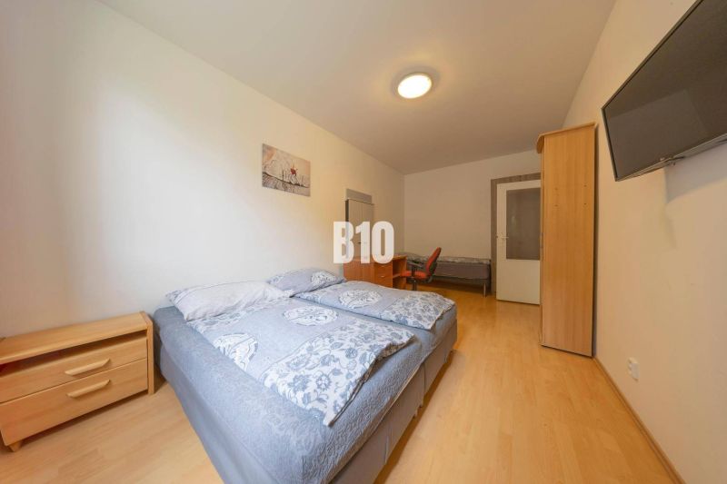 Ein Schlafzimmer mit zwei Betten, einem Nachttisch, einem Schrank und einem Fernseher an der Wand.