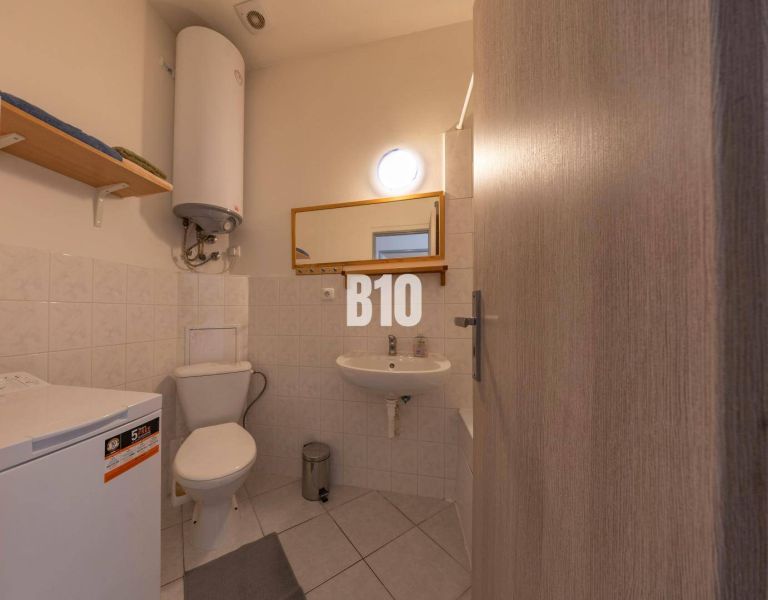 Badezimmer mit Waschmaschine, Waschbecken, Spiegel und Boiler im Büro.