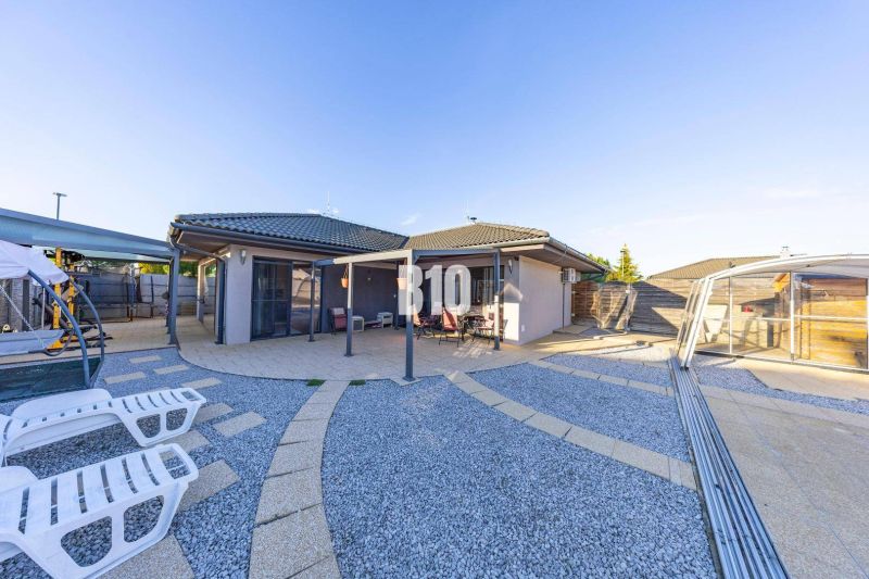 Ein Einfamilienhaus in Most pri Bratislave mit einer Terrasse und einem von Kieselsteinen umgebenen Pool.