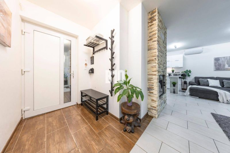 Innenraum eines Einfamilienhauses mit Holzboden, Steinkamin und gemütlichem Wohnzimmer.