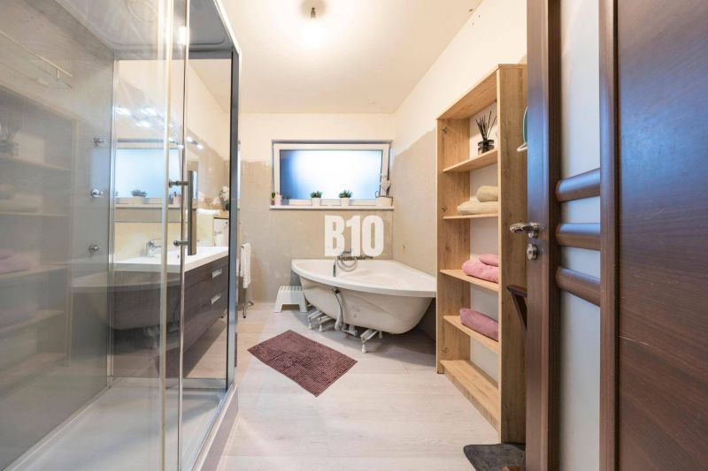 Ein Badezimmer in einem Einfamilienhaus mit Badewanne, Dusche und Möbeln mit Holzdekor.