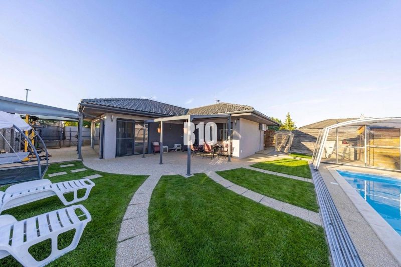 Ein Einfamilienhaus in Most pri Bratislave mit Terrasse, Pool und Liegestühlen im Garten.